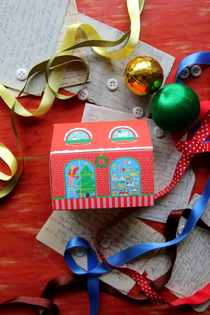 Decorative match box with festive design on a red surface with ribbons and ornaments.