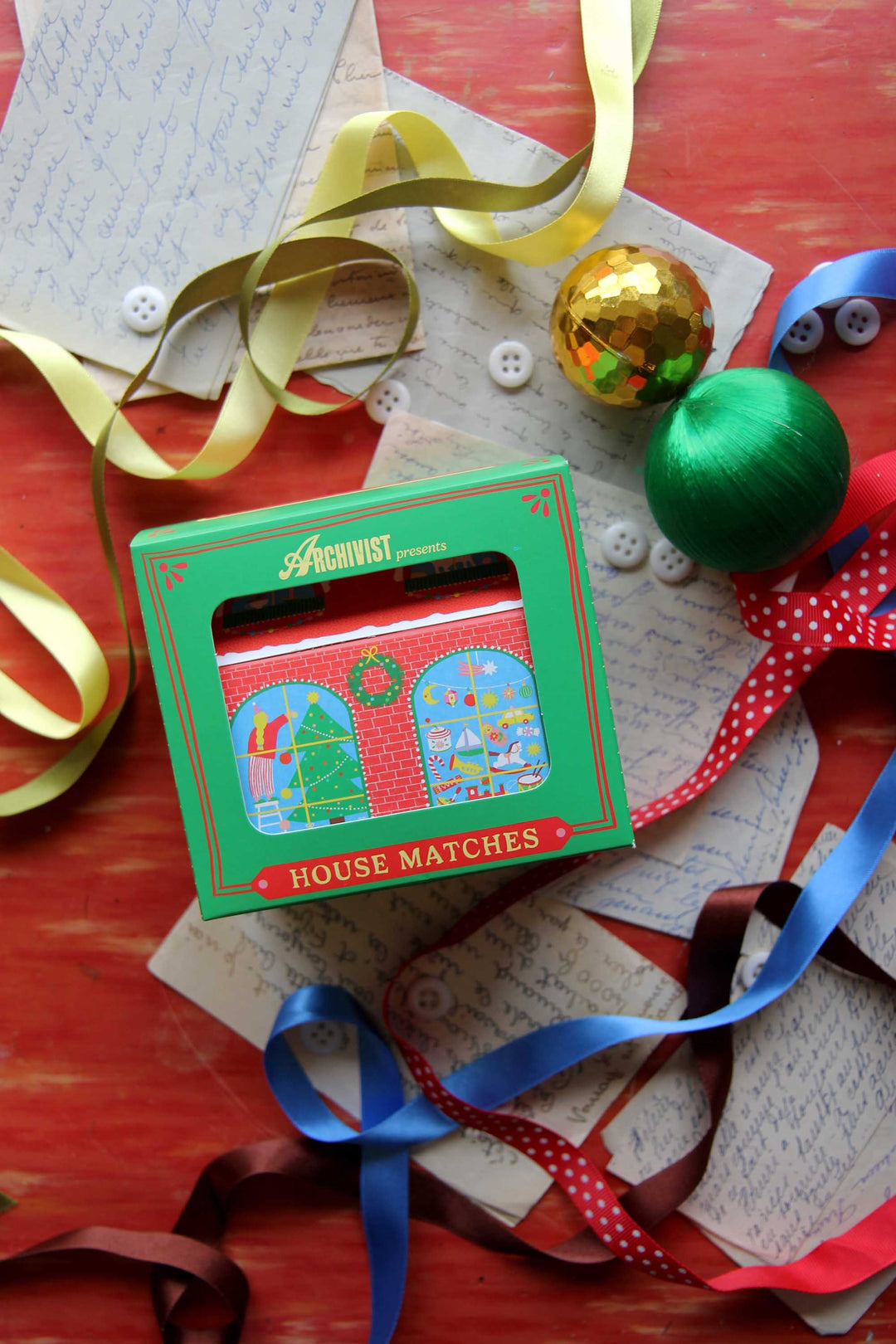 Matchbox with festive design on a table with ribbons and decorations
