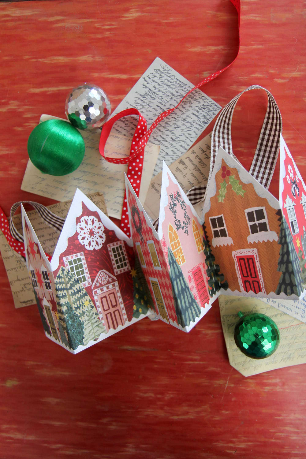 Decorative paper houses with green ornaments on a wooden surface
