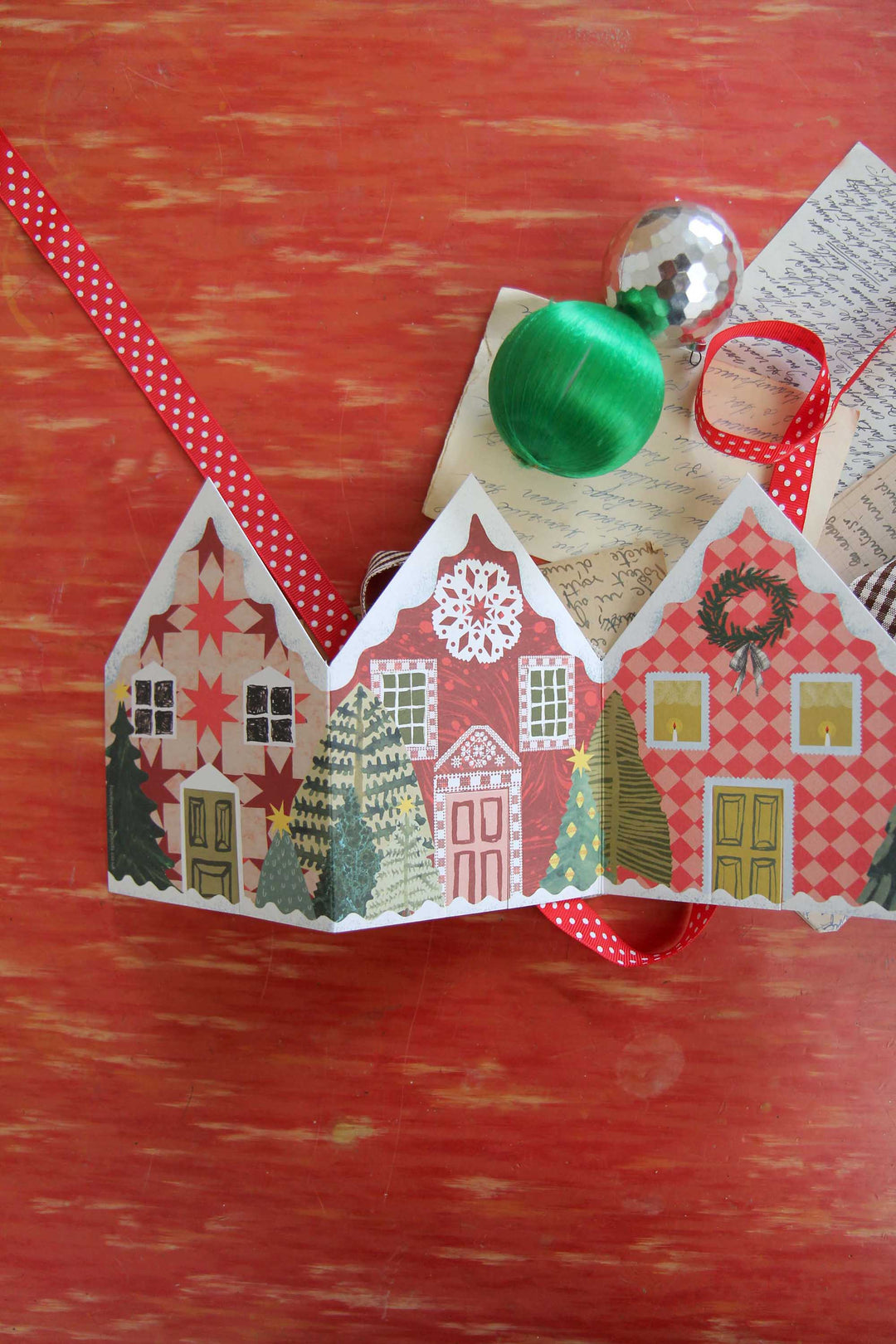 Decorative Christmas village scene with houses and ornaments on a red background