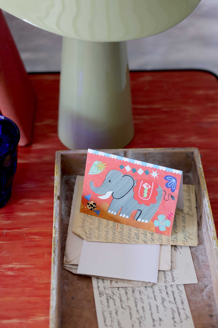 Card with an elephant design on top of old letters in a wooden box.