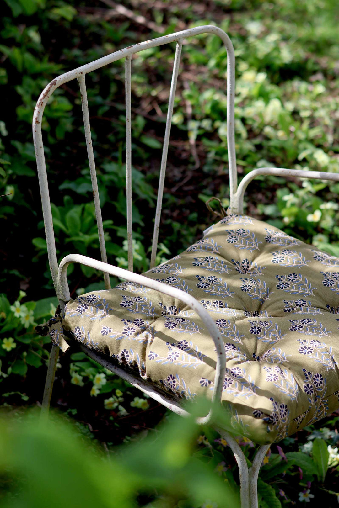 White metal chair with patterned cushion in a garden setting