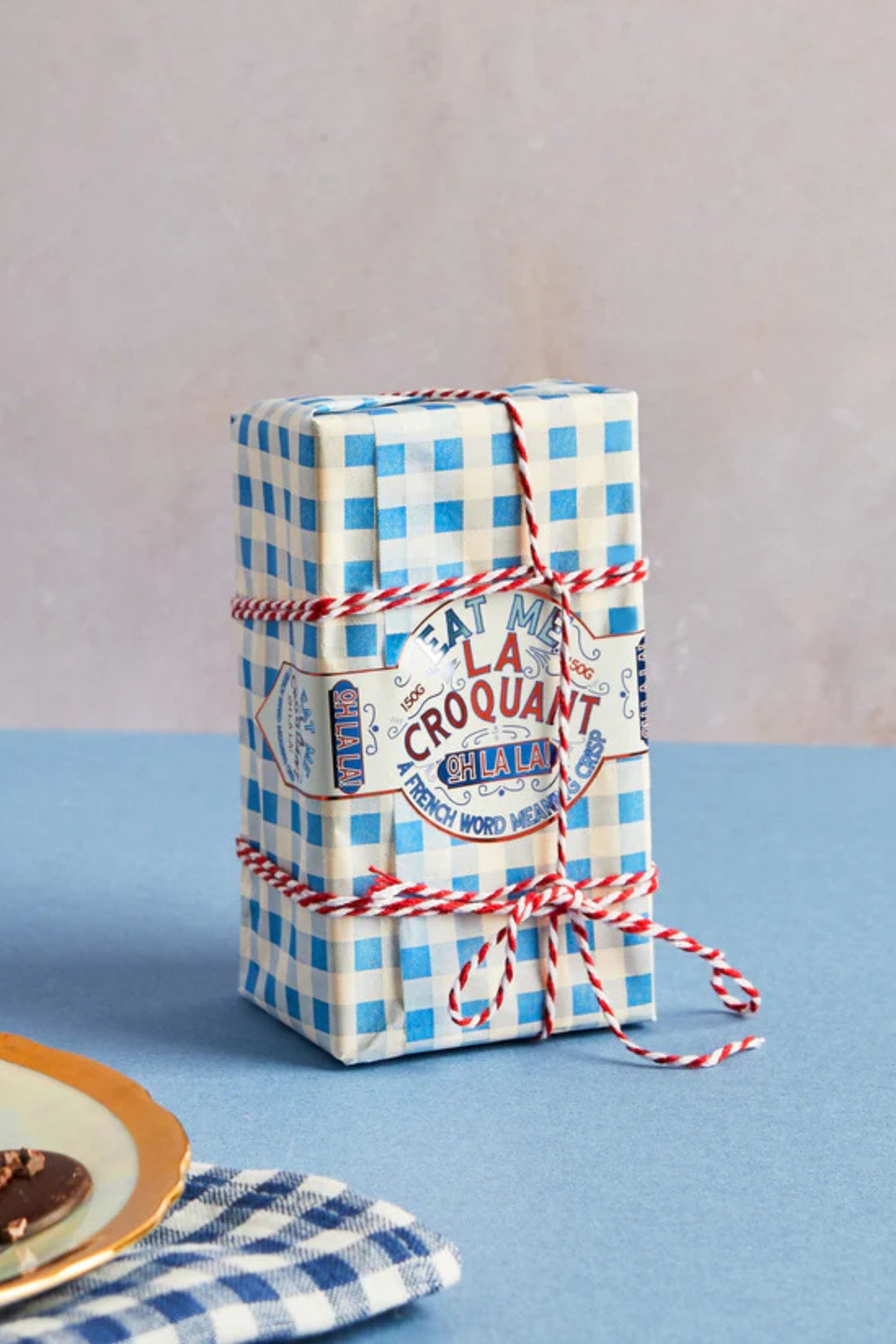 Gift box with blue and white checkered paper and red string on a blue surface.