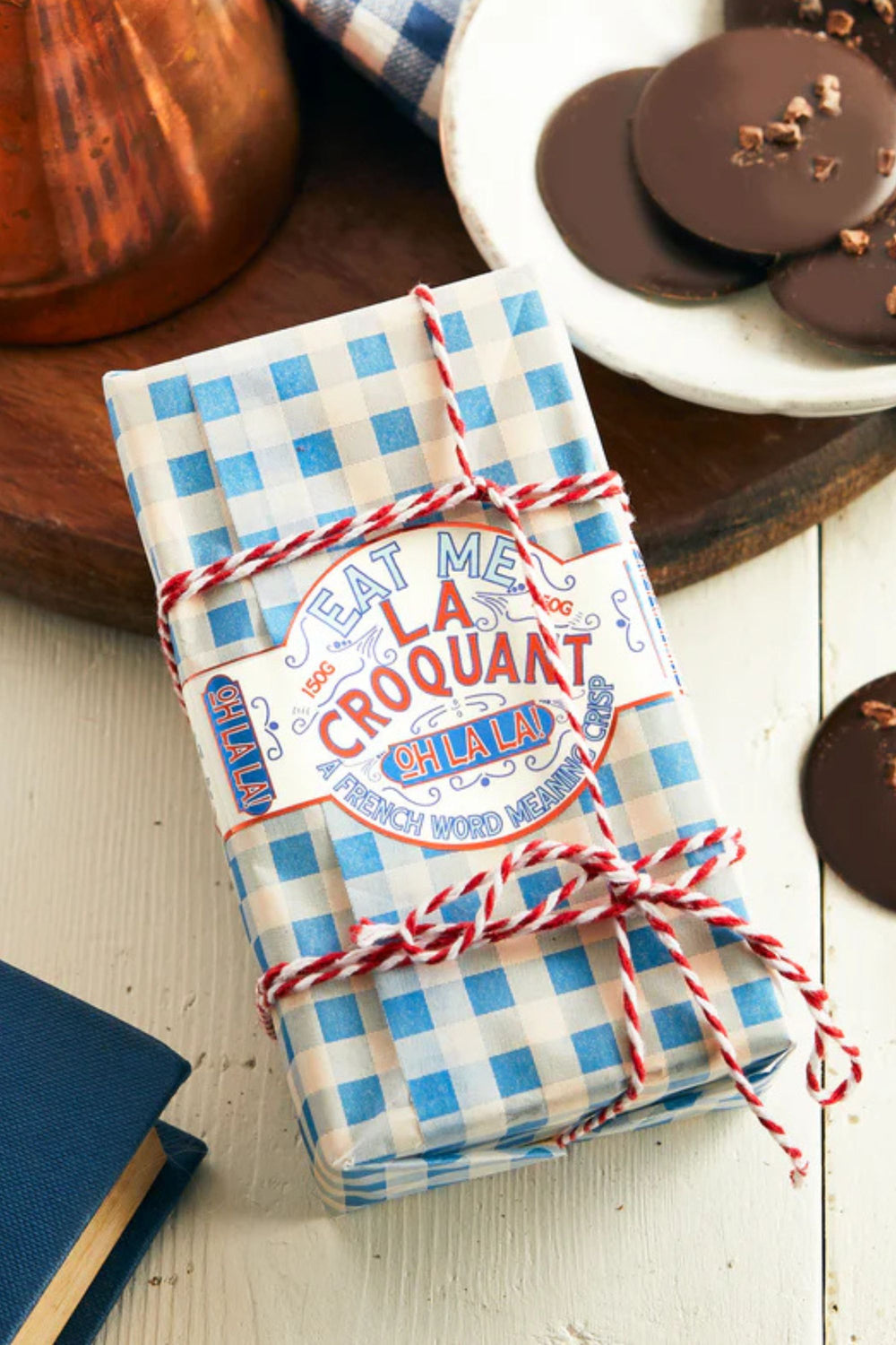 Packaged product with blue and white checkered design and red string on a wooden surface.