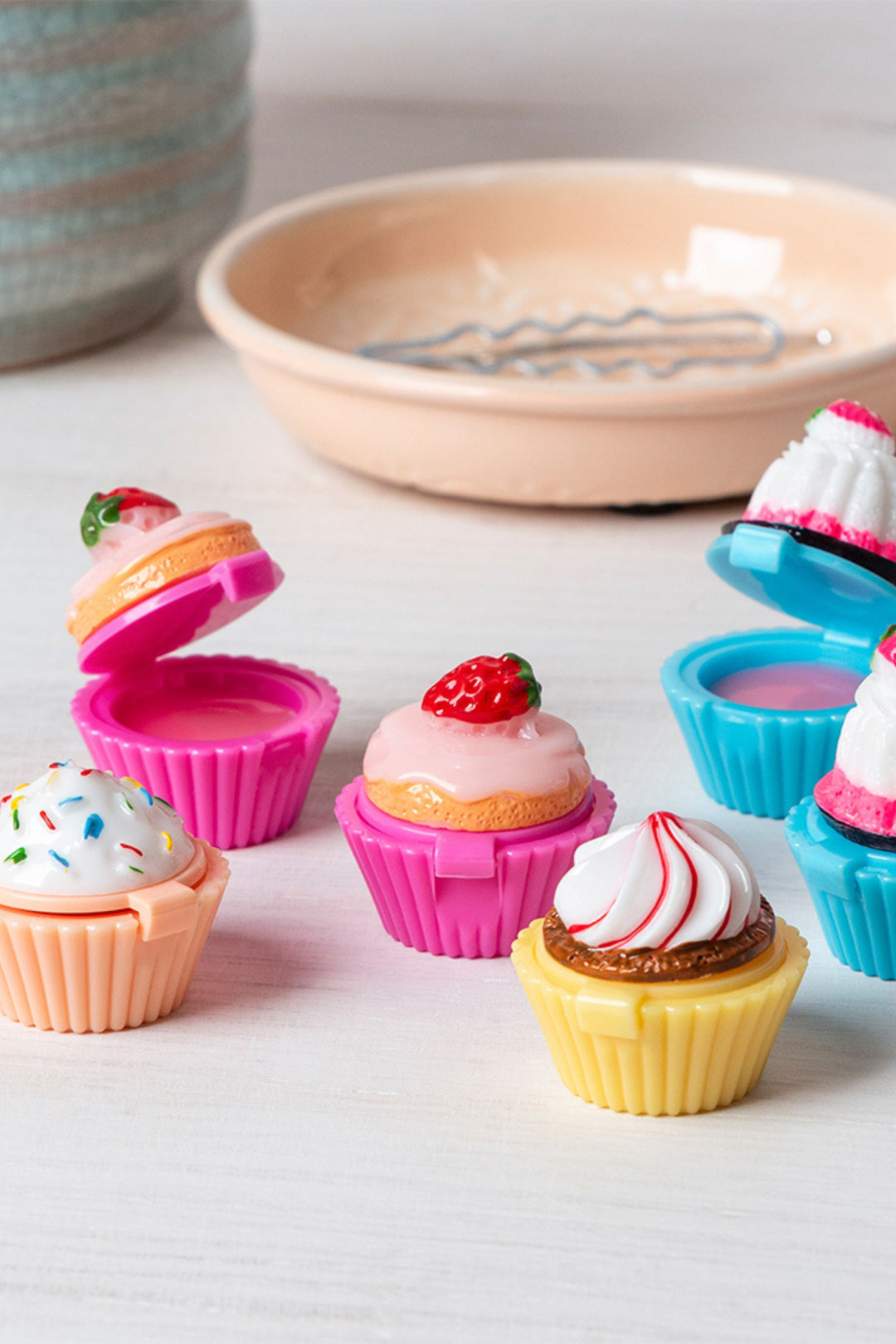 Colorful cupcake-shaped containers with lids on a light surface.