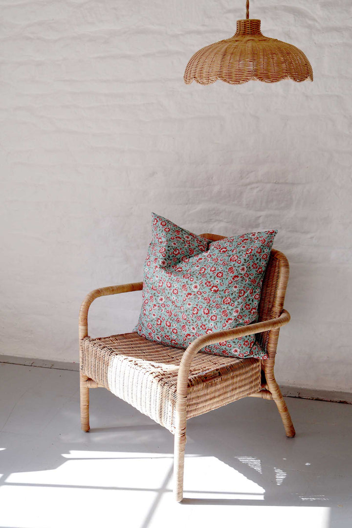 Wicker chair with floral cushions against a white wall