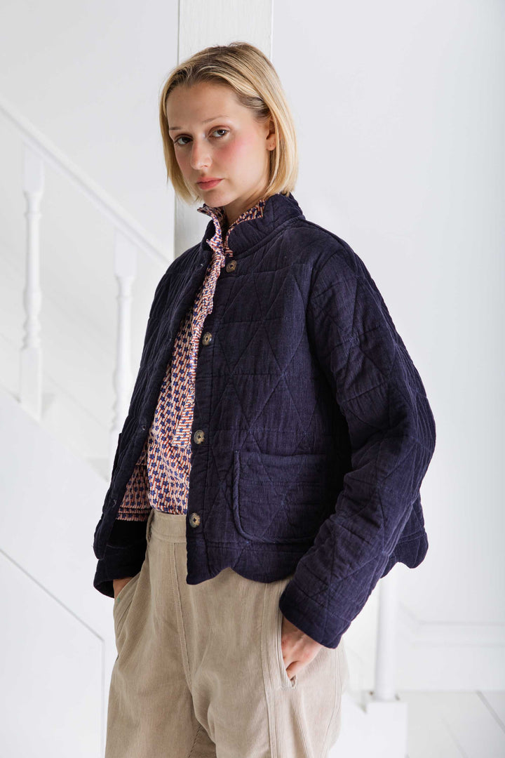Woman wearing a dark blue quilted jacket against a white background