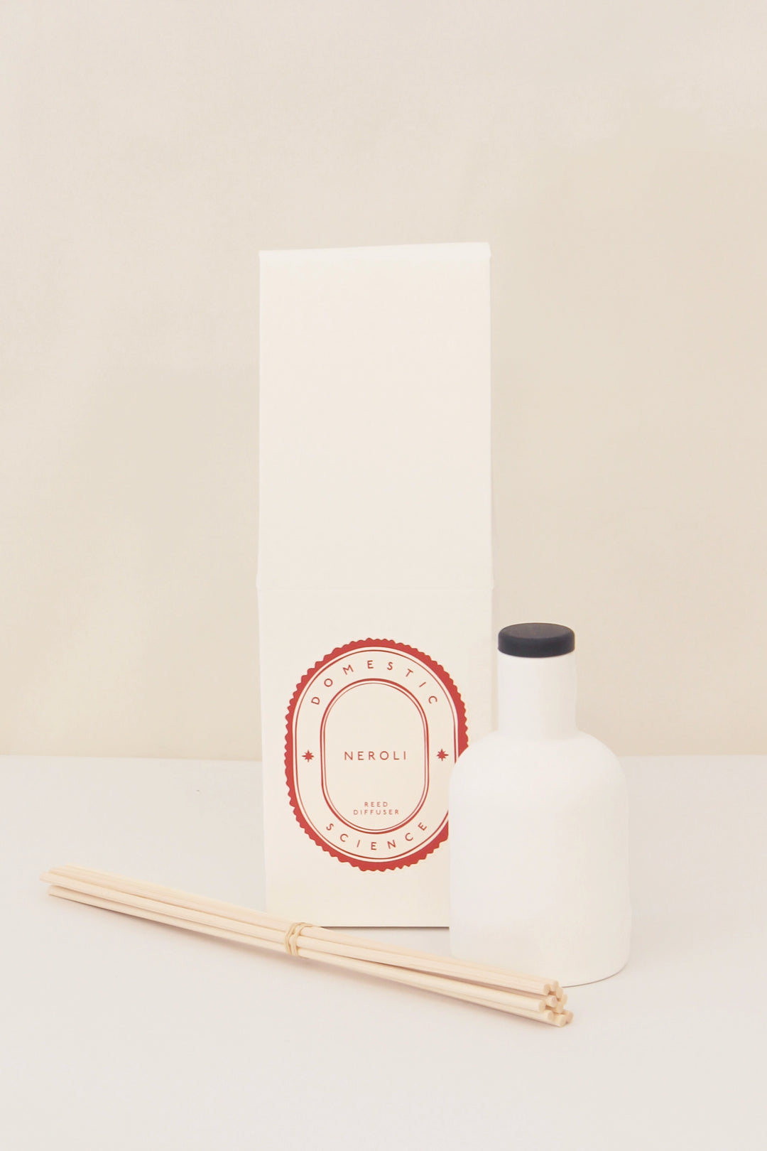 neroli diffuser and ceramic vessel and reeds on white background