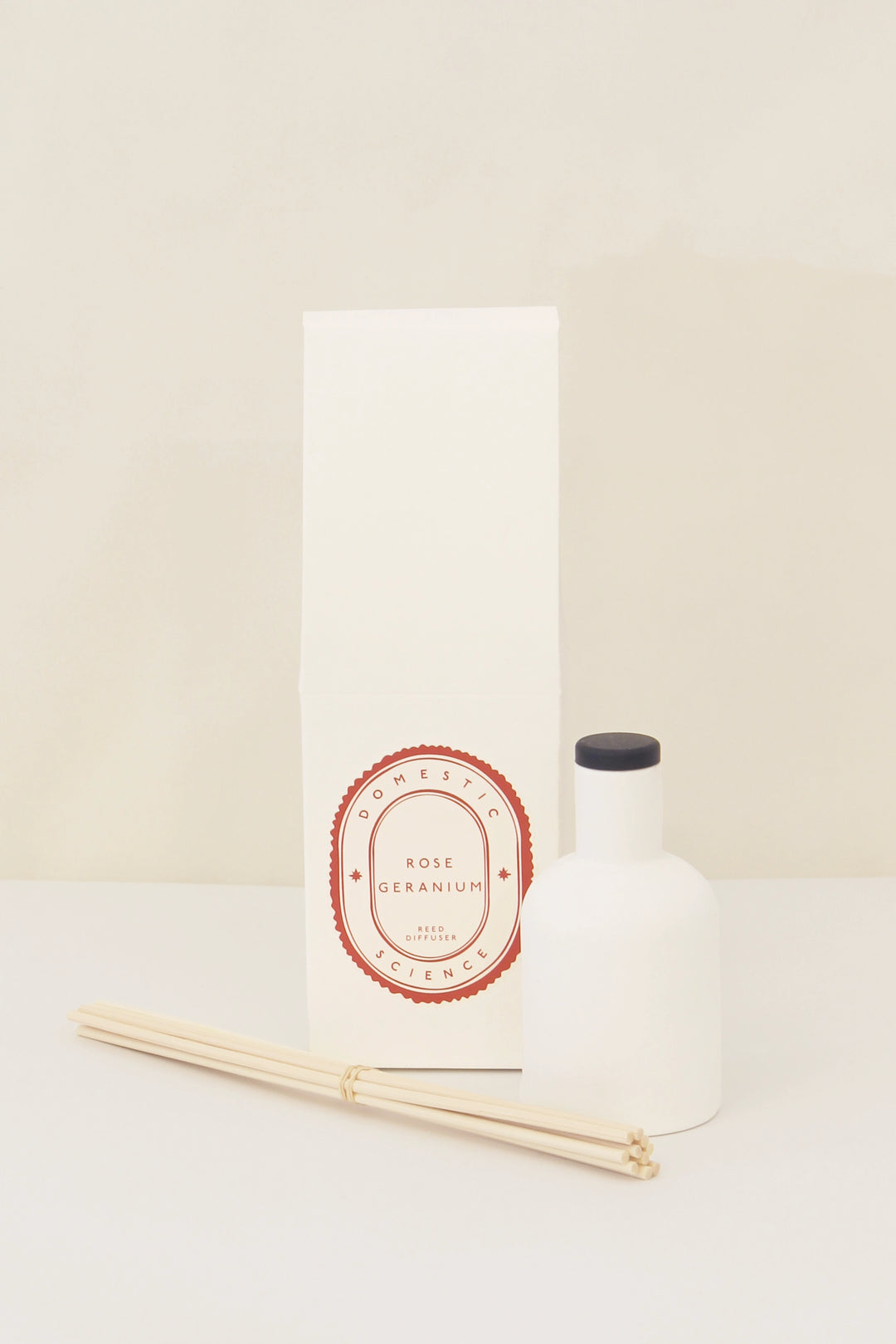 rose geranium diffuser and ceramic vessel and reeds on white background