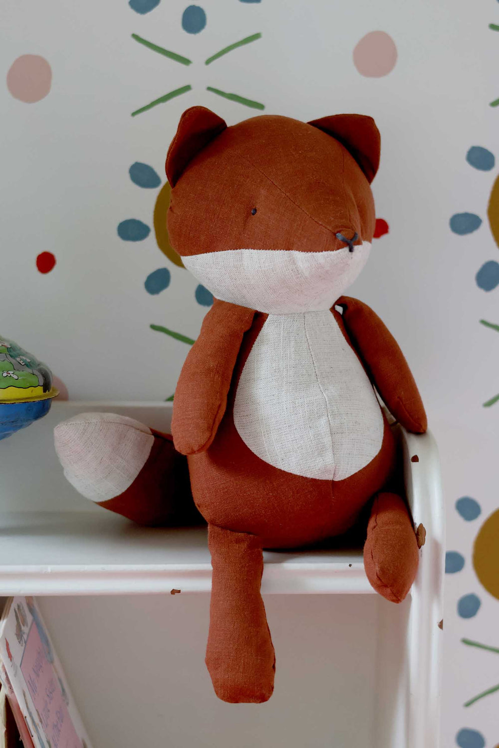 Plush fox toy on a shelf with a polka dot wall in the background