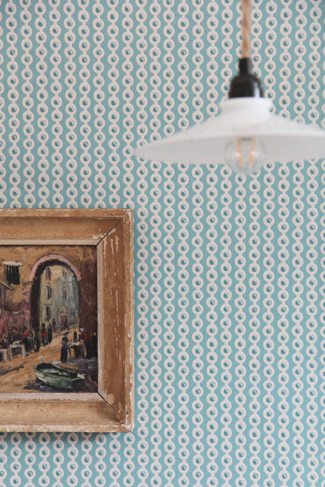 deauville spot wallpaper in celadon blue with vintage hanging light and vintage painting hanging on the wall