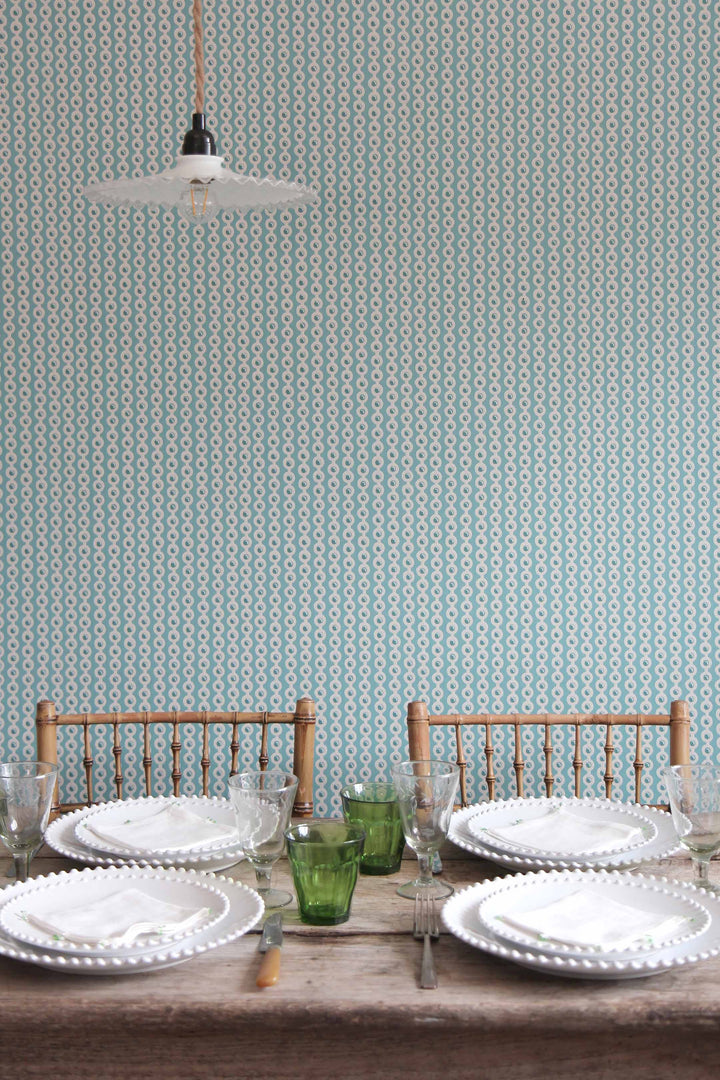 deauville spot wallpaper in celadon blue in dining room scene. table laid with white pearl tableware, green duralex glasses and vintage bamboo dining chairs