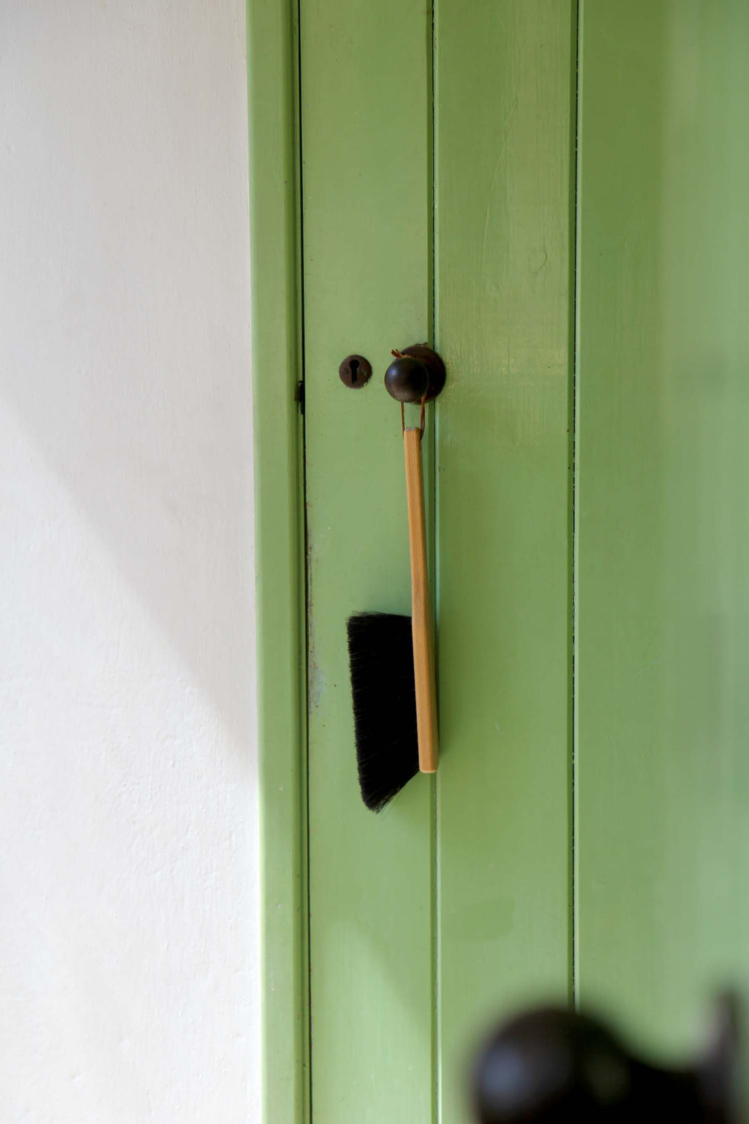 Green cabinet with a brush hanging on a handle