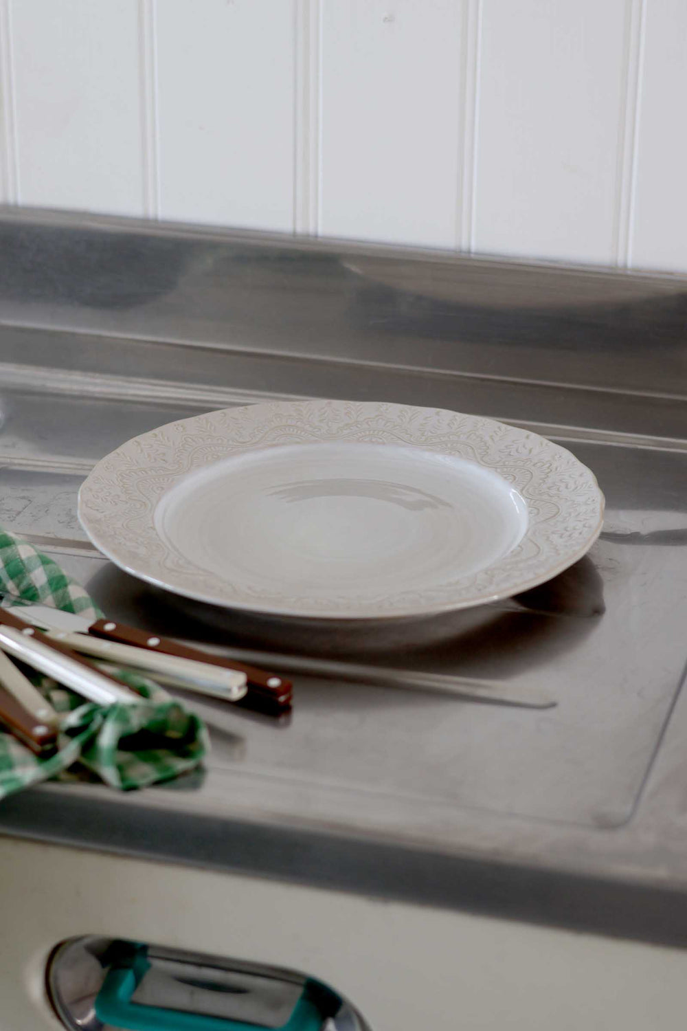 White plate on a metallic surface with a white cabinet in the background