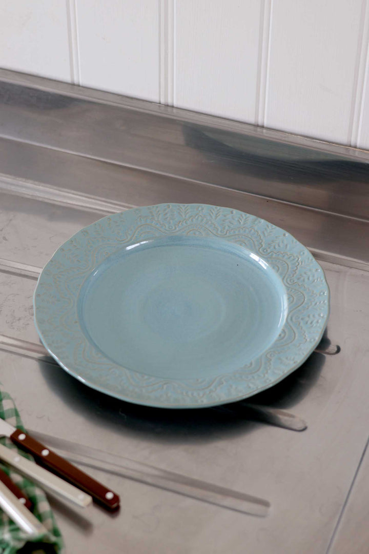 Light blue decorative plate on a wooden surface with chopsticks and a green cloth.