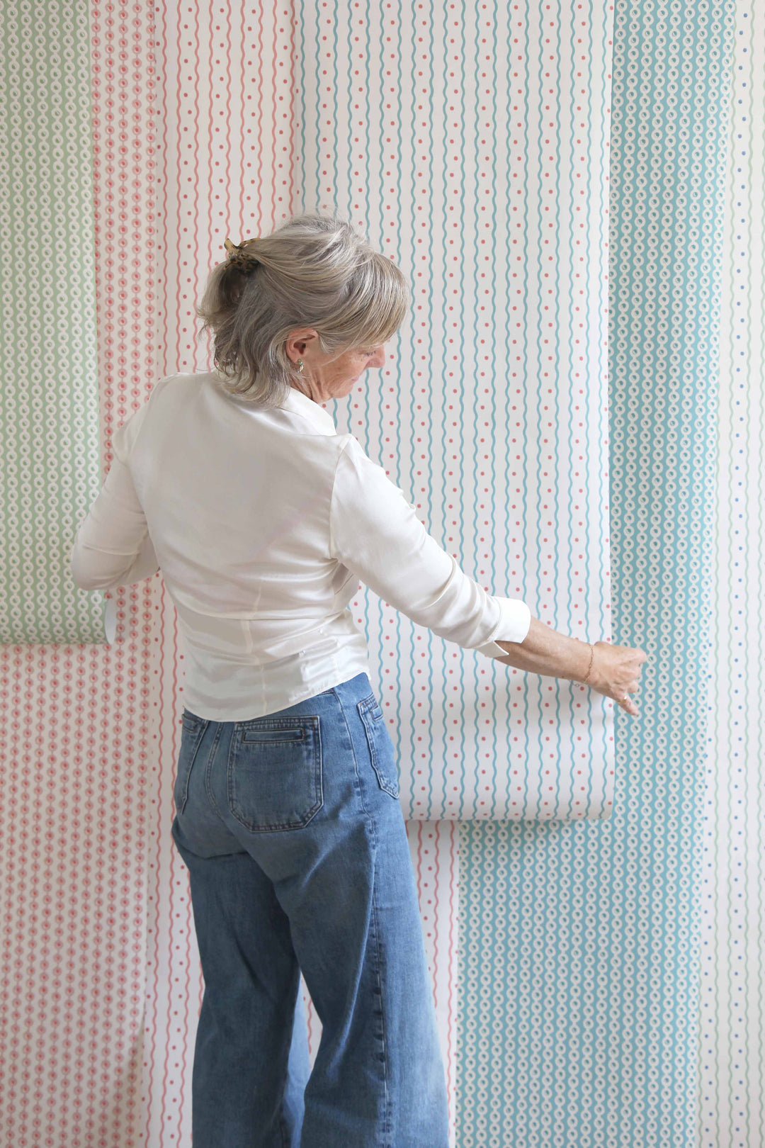 libs nicholls standing in front of hanging rolls of her wallpaper collection for domestic science home