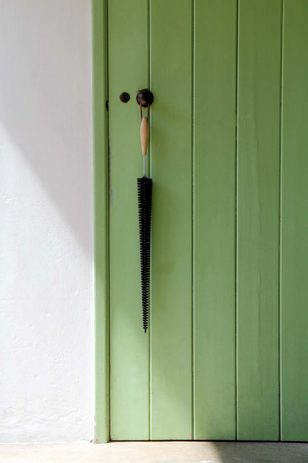 Green door with a black brush against it