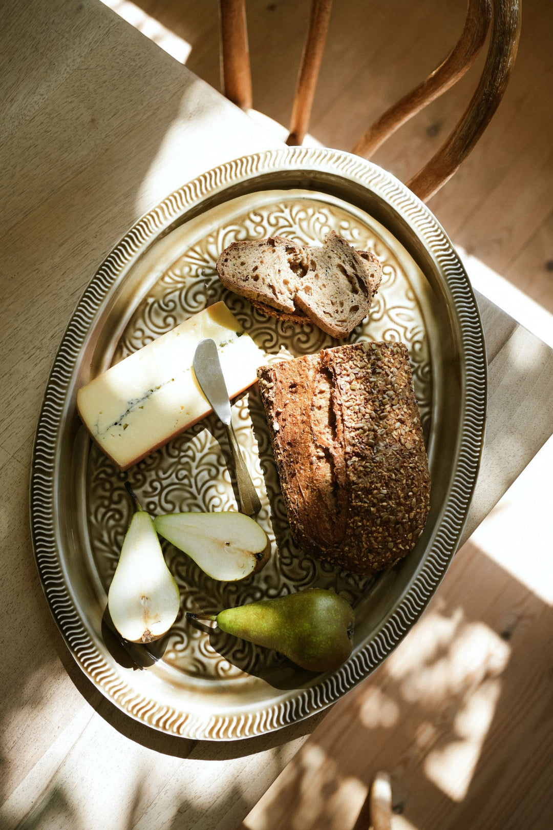 Platter with bread, cheese, and pears on a wooden surface