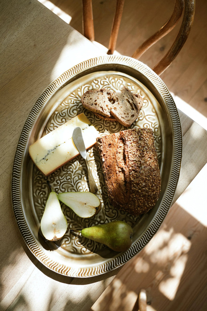 Platter with bread, cheese, and pears on a wooden surface