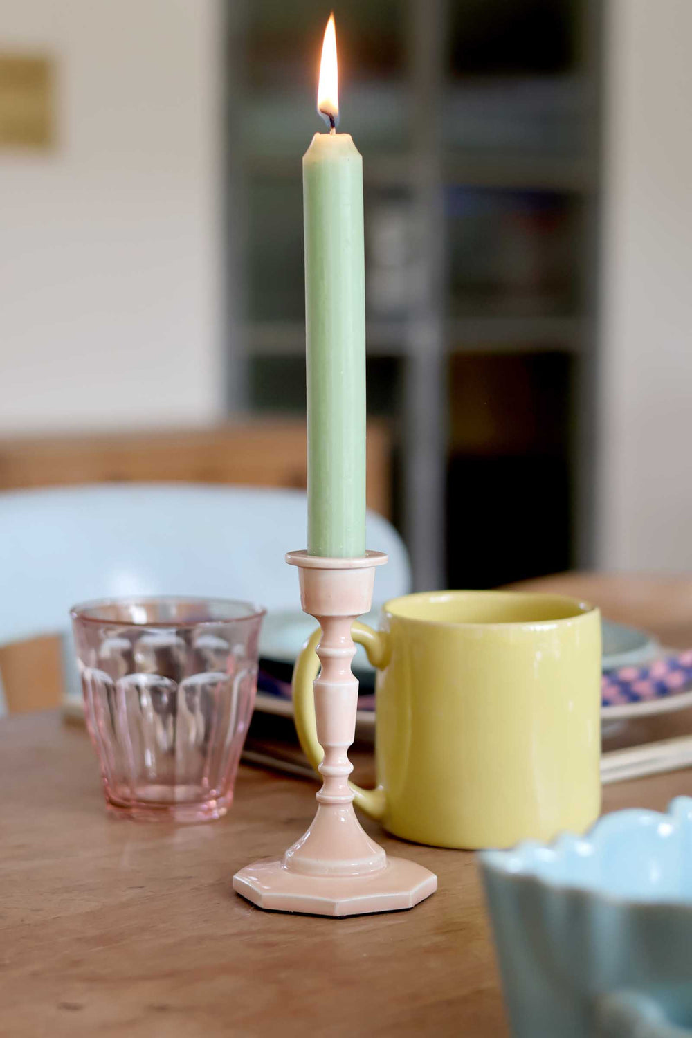 Green candle in a decorative holder on a wooden table with a blurred background