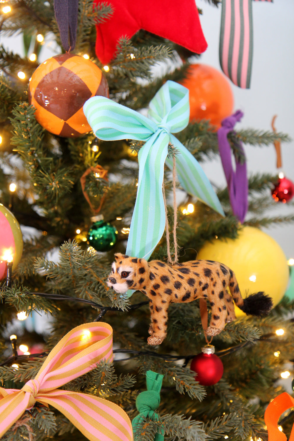 Decorative Christmas tree with colorful ornaments and a leopard figurine.