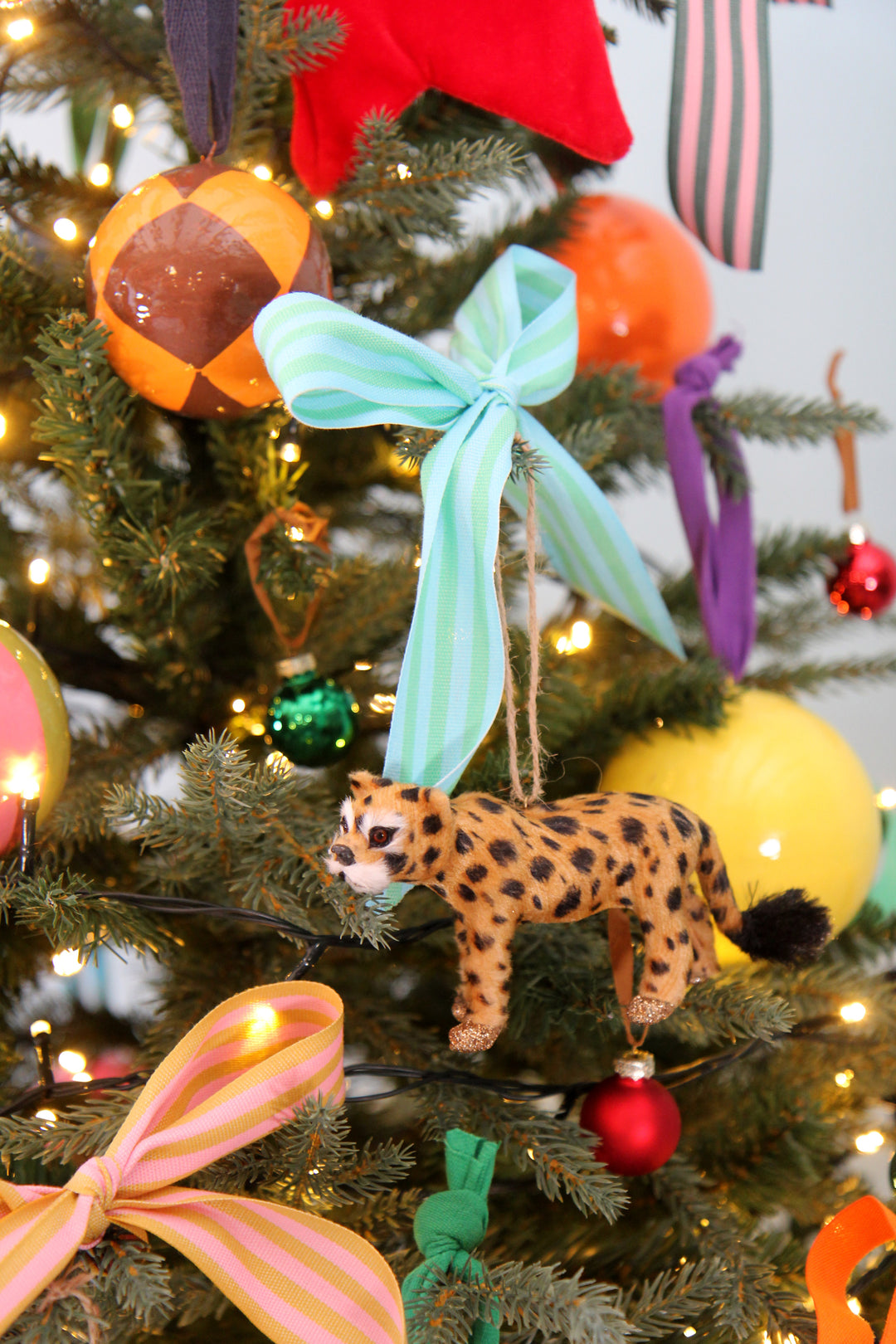 Decorative Christmas tree with colorful ornaments and a leopard figurine.