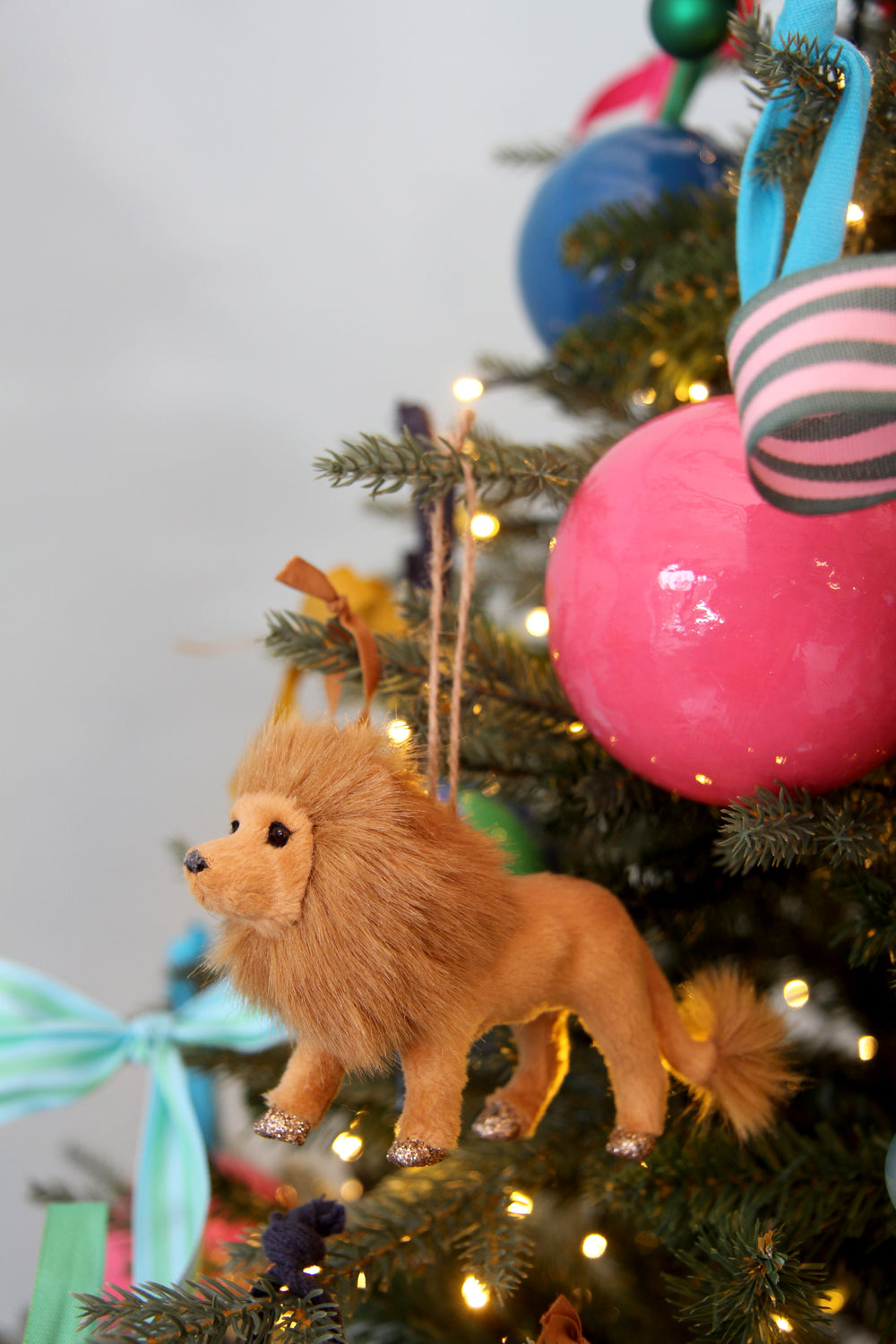 Toy lion on a decorated Christmas tree with colorful ornaments and lights.
