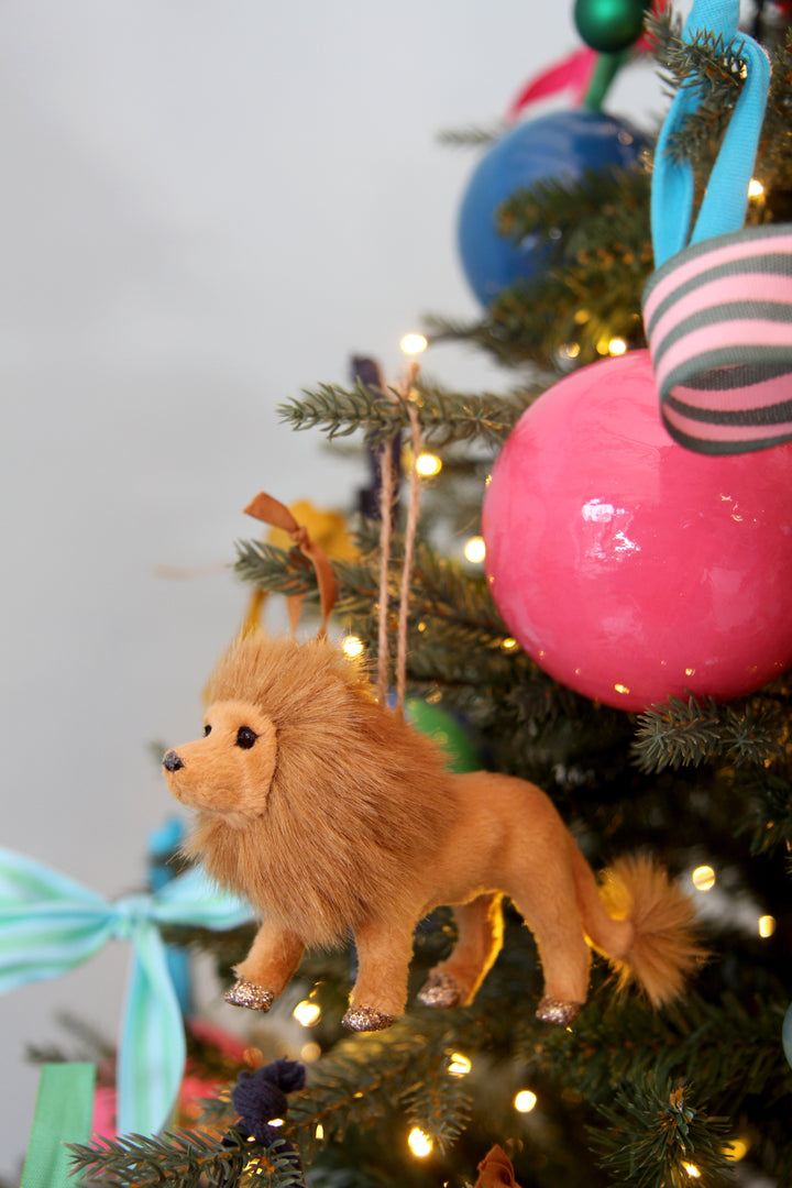 Toy lion on a decorated Christmas tree with colorful ornaments and lights.