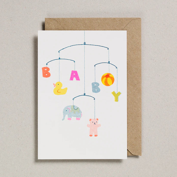 Greeting card with baby mobile design featuring colorful animals and 'BABY' letters, with a brown envelope.