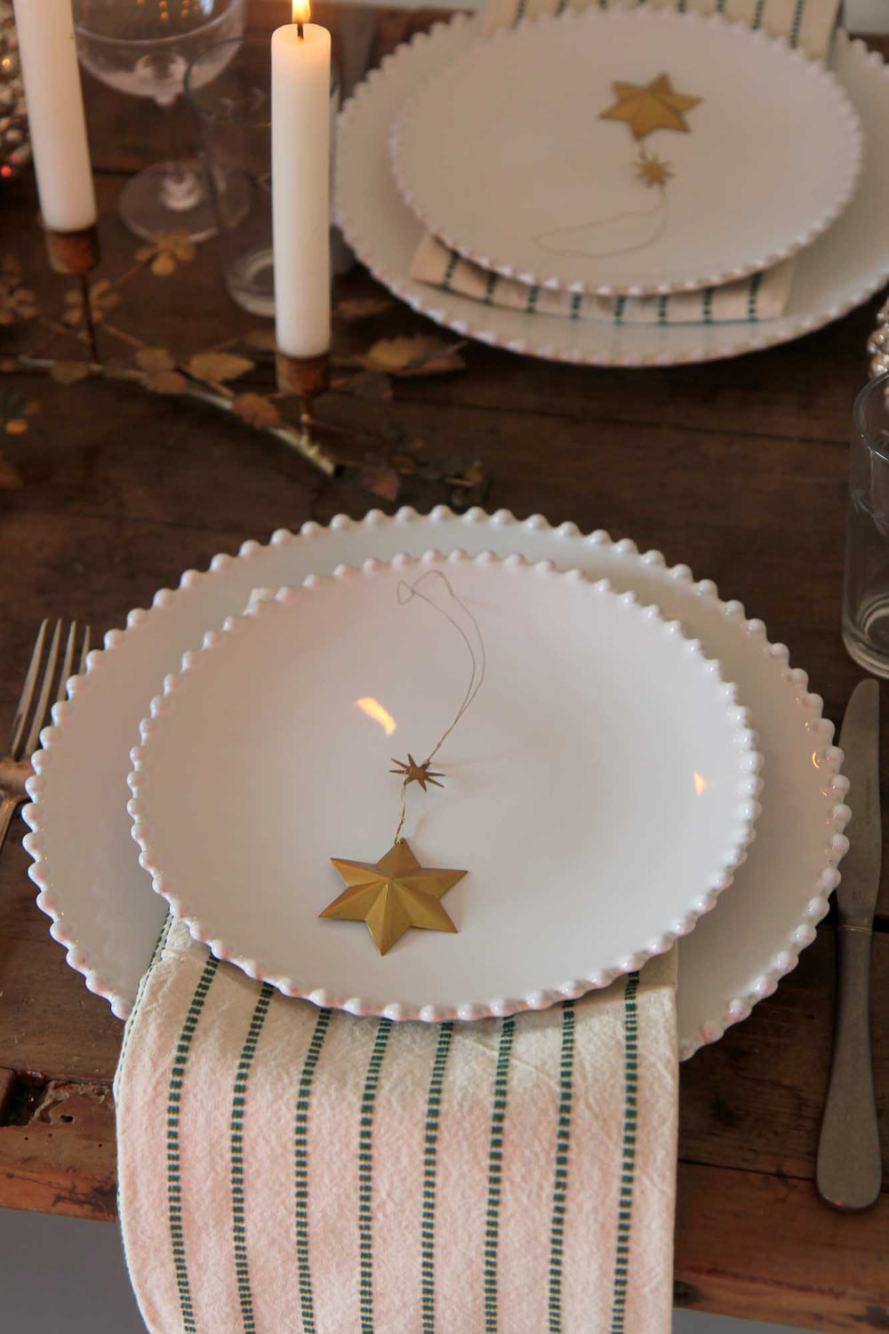 Set table with white plates featuring gold star decorations on a wooden surface.