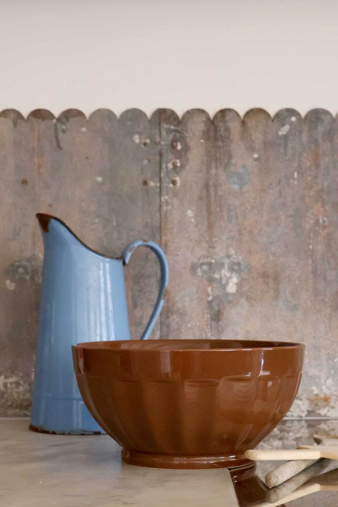 Brown bowl and blue pitcher against a rustic wooden fence background