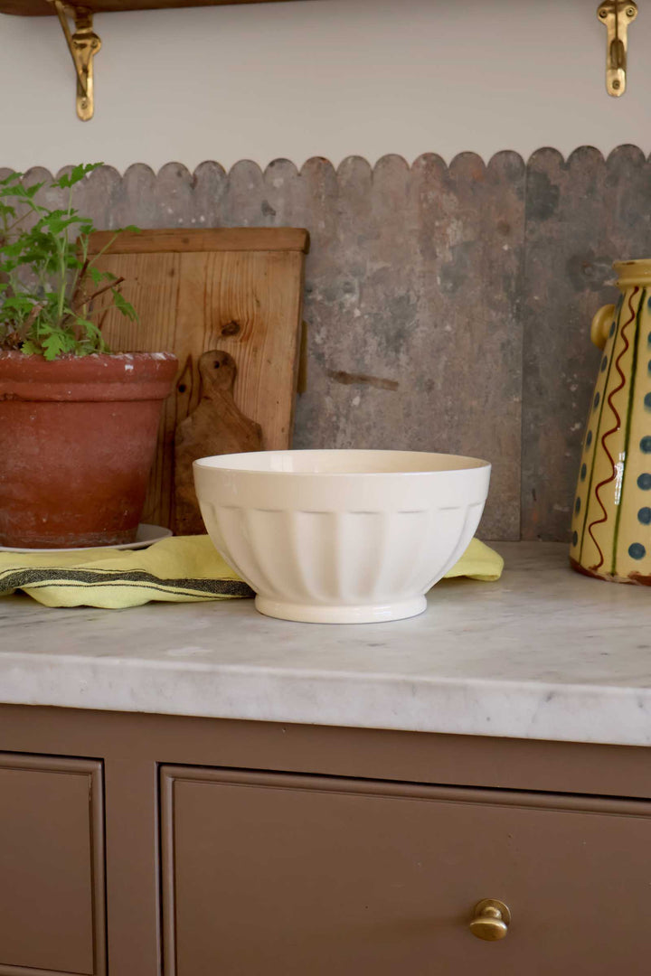 White bowl on a kitchen counter with a rustic metal backsplash and wooden cabinet.