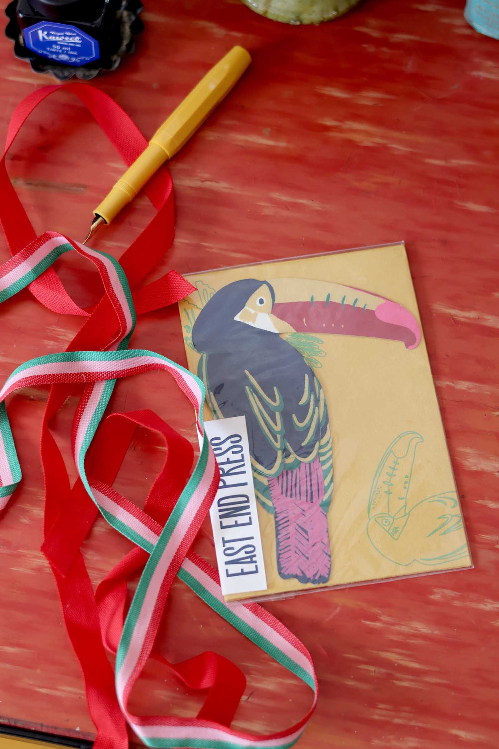 Card with bird illustration and ribbons on a red surface