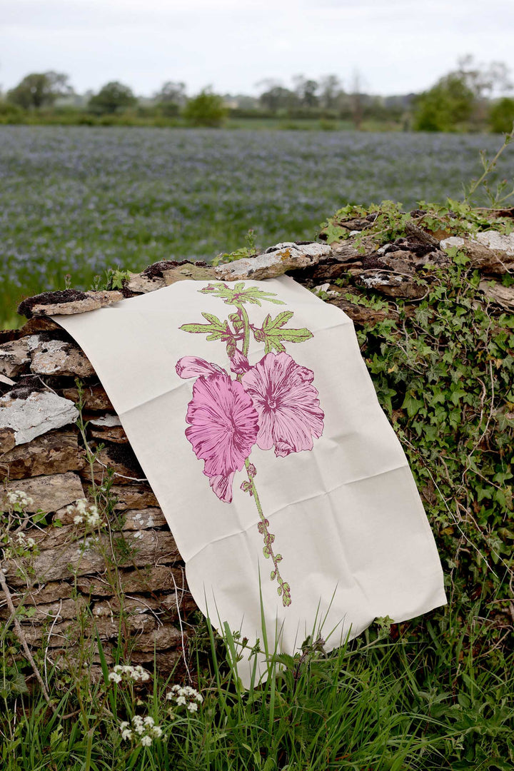 Floral-patterned fabric draped over a stone wall with a field in the background