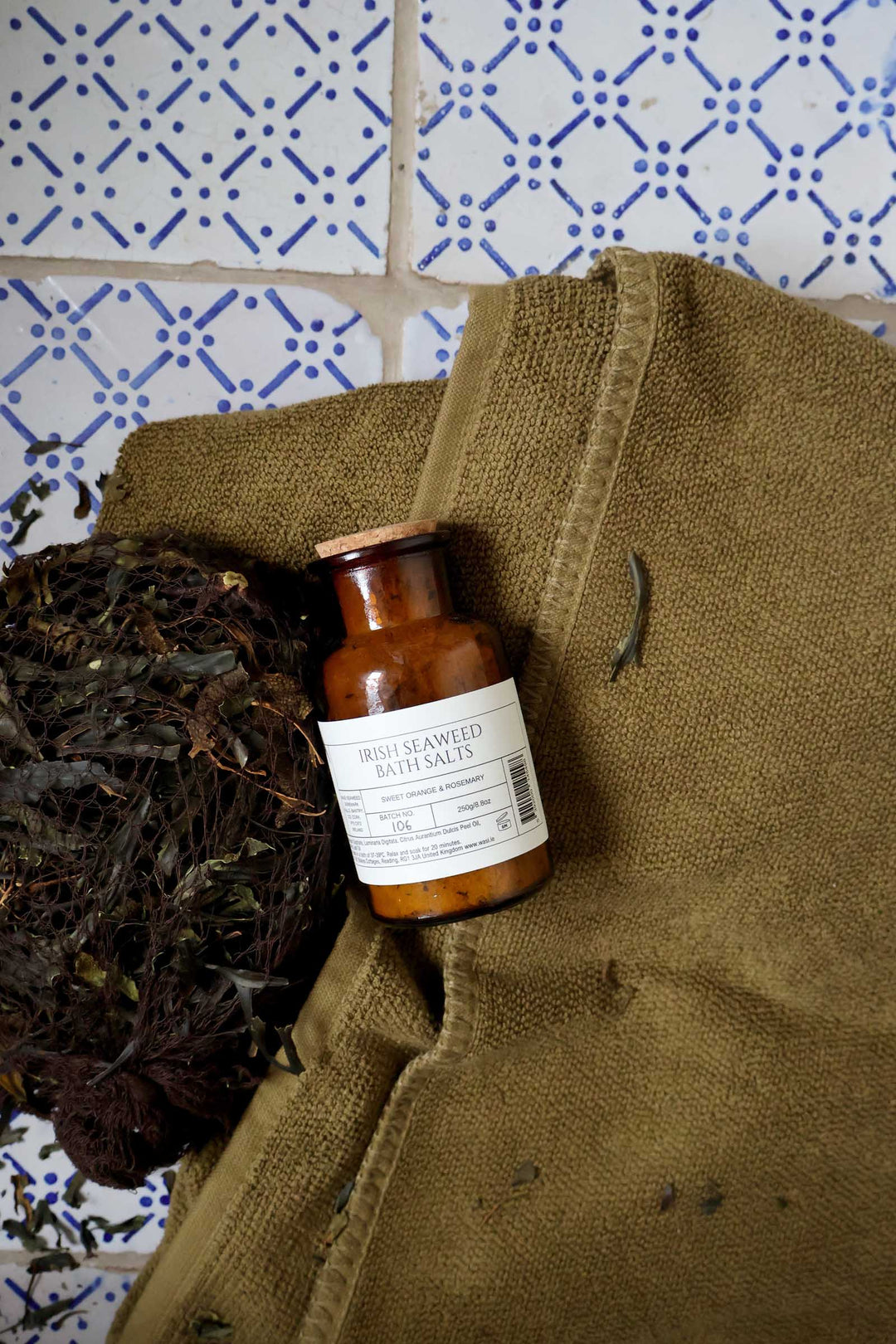 Small brown bottle with a label on a textured surface with a patterned tile background