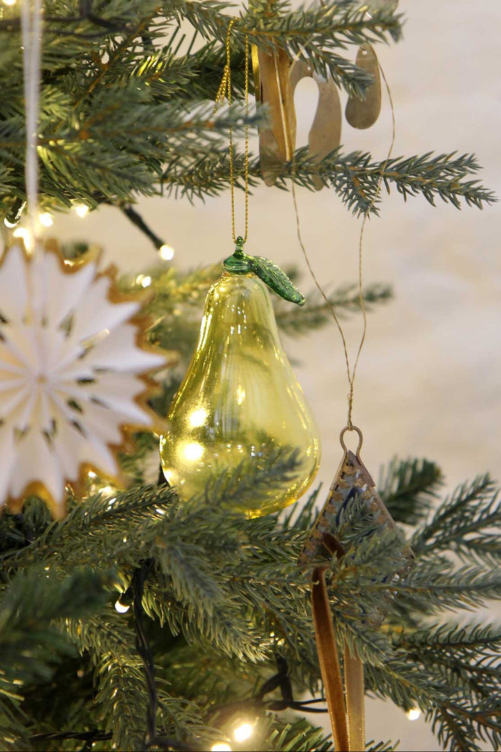 Decorative Christmas tree with green glass ornament and lights on a neutral background