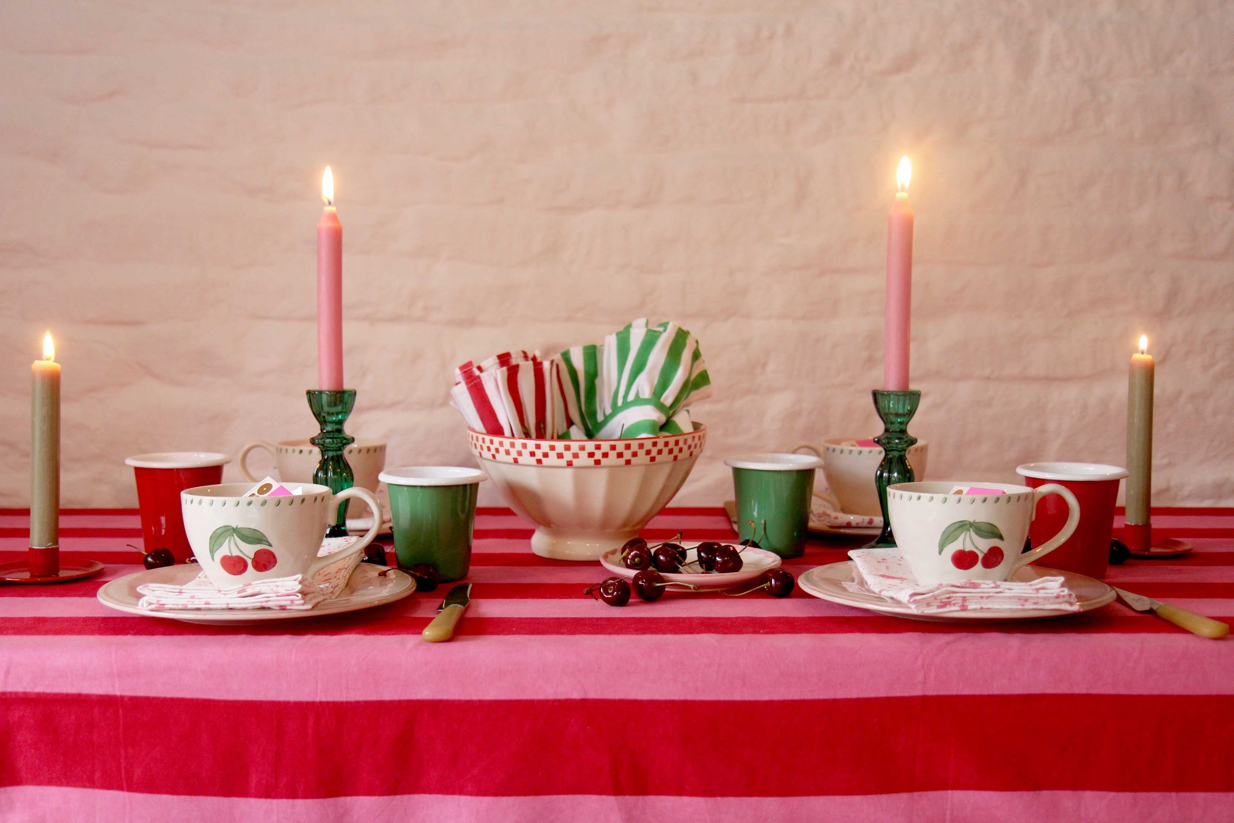 pink and red themed tablescape with cherry tableware and ambient pink dinner candles