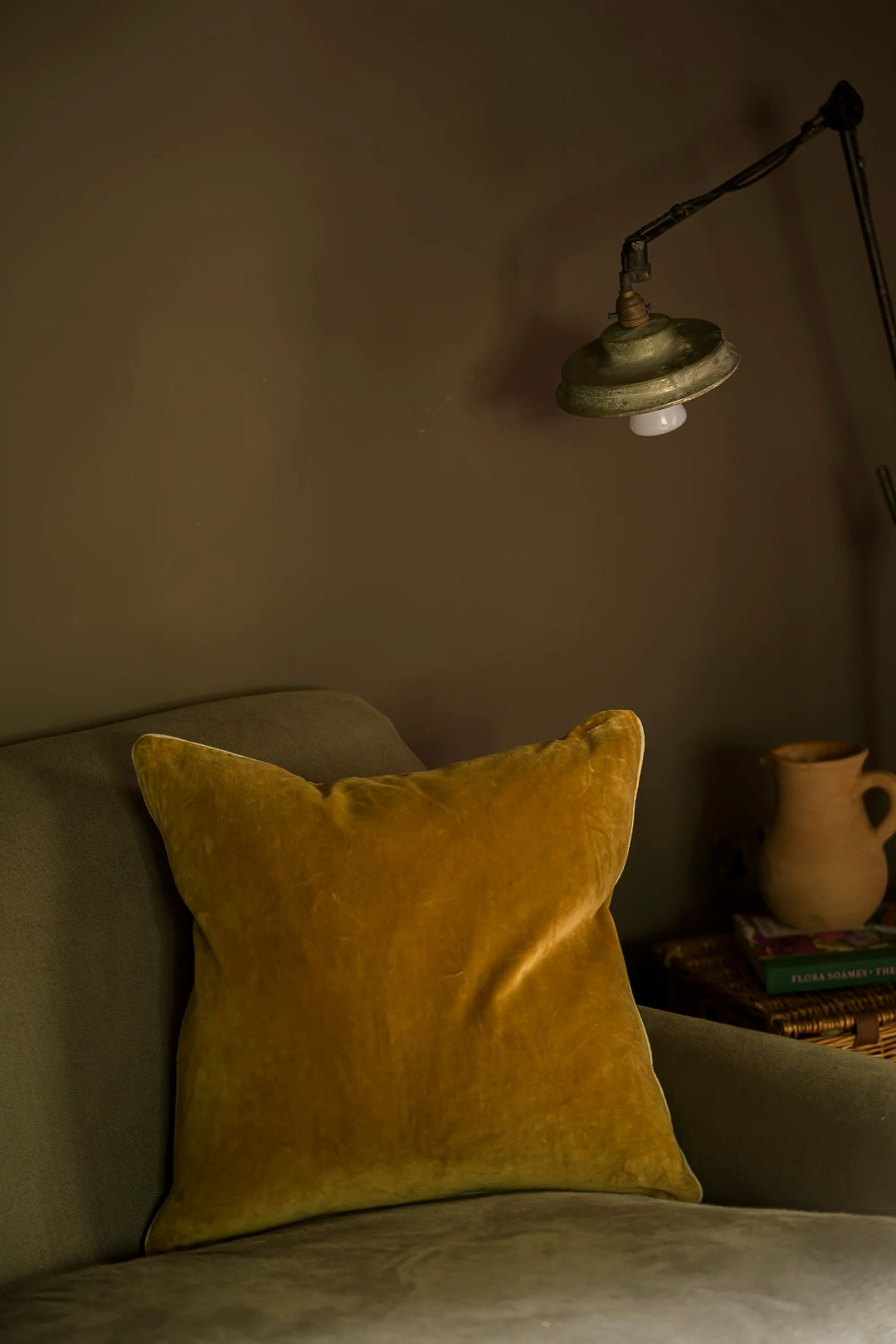 Yellow pillow on a gray sofa with a vintage-style lamp in a dimly lit room.