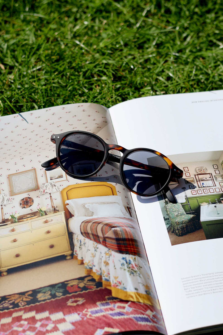 Sunglasses on an open book with a bedroom scene