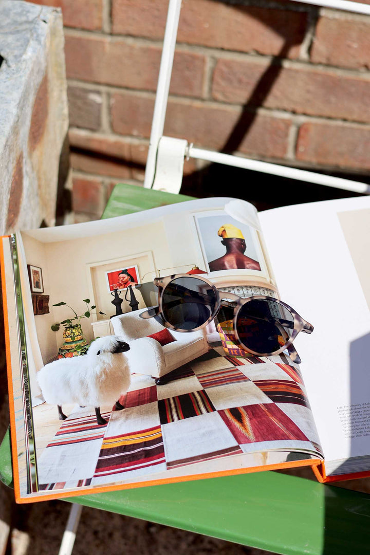 Open book with sunglasses on a checkered surface, brick wall in the background