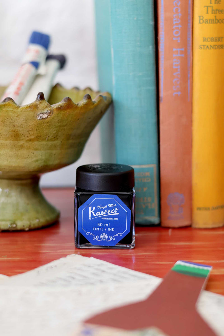 Kaweco ink bottle on a wooden surface with books in the background