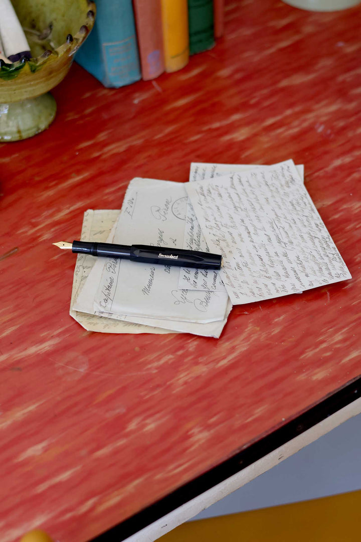 Pen and paper on a red surface with books in the background