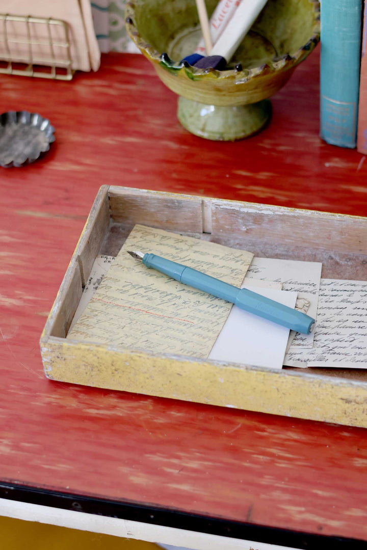 Wooden box with paper and a pen on a red surface