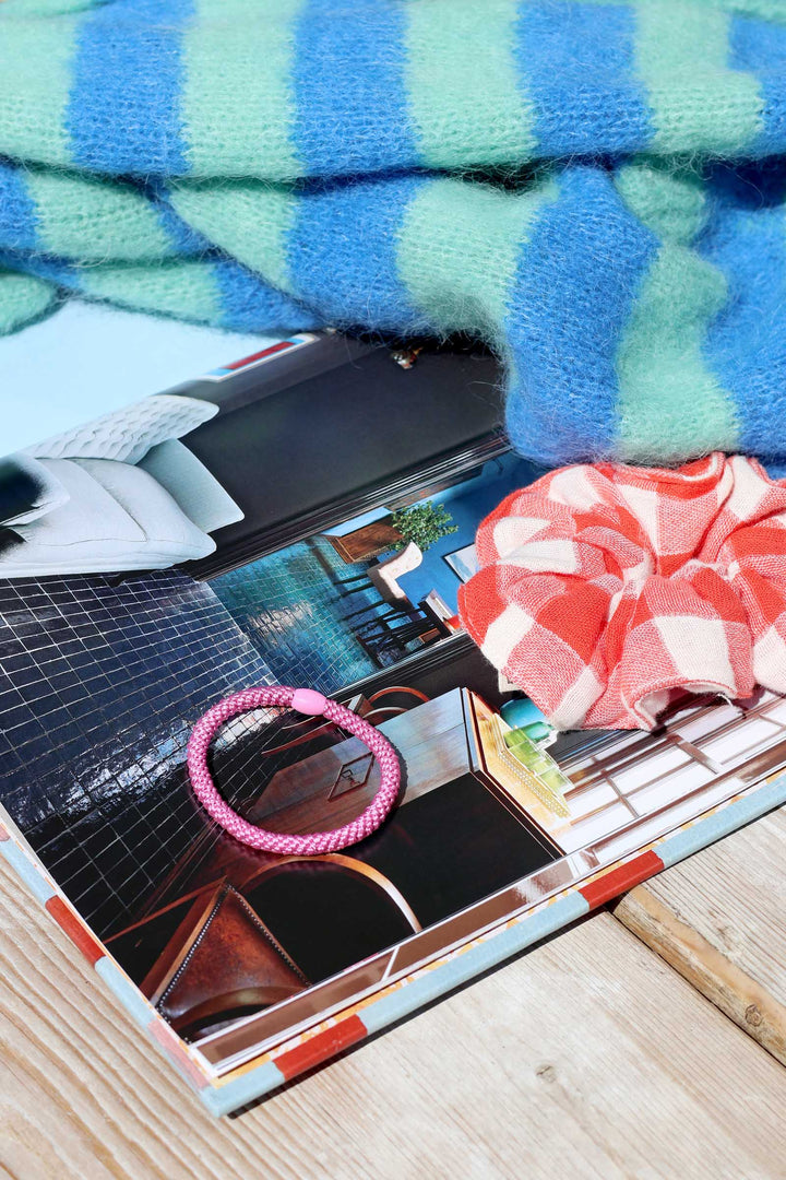 Makeup palette with pink hair tie and scrunchie on a colorful towel