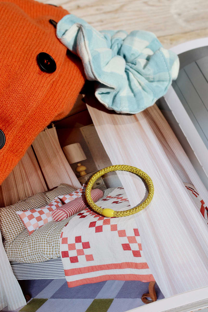 Close-up of a decorative mirror with a yellow frame on a bed with patterned bedding.