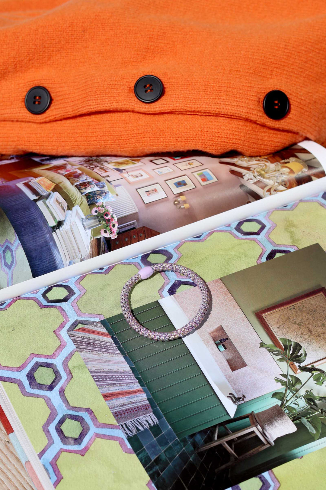 Close-up of an orange fabric with buttons and a design book with interior design images.