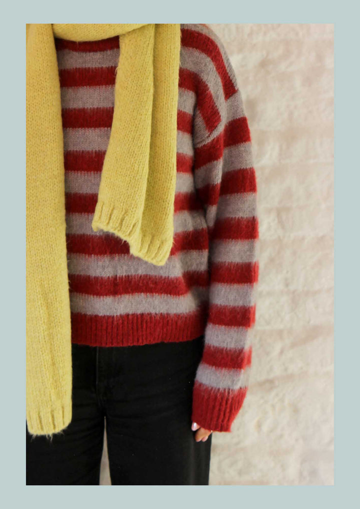 Red and white striped sweater with a yellow scarf on a light background