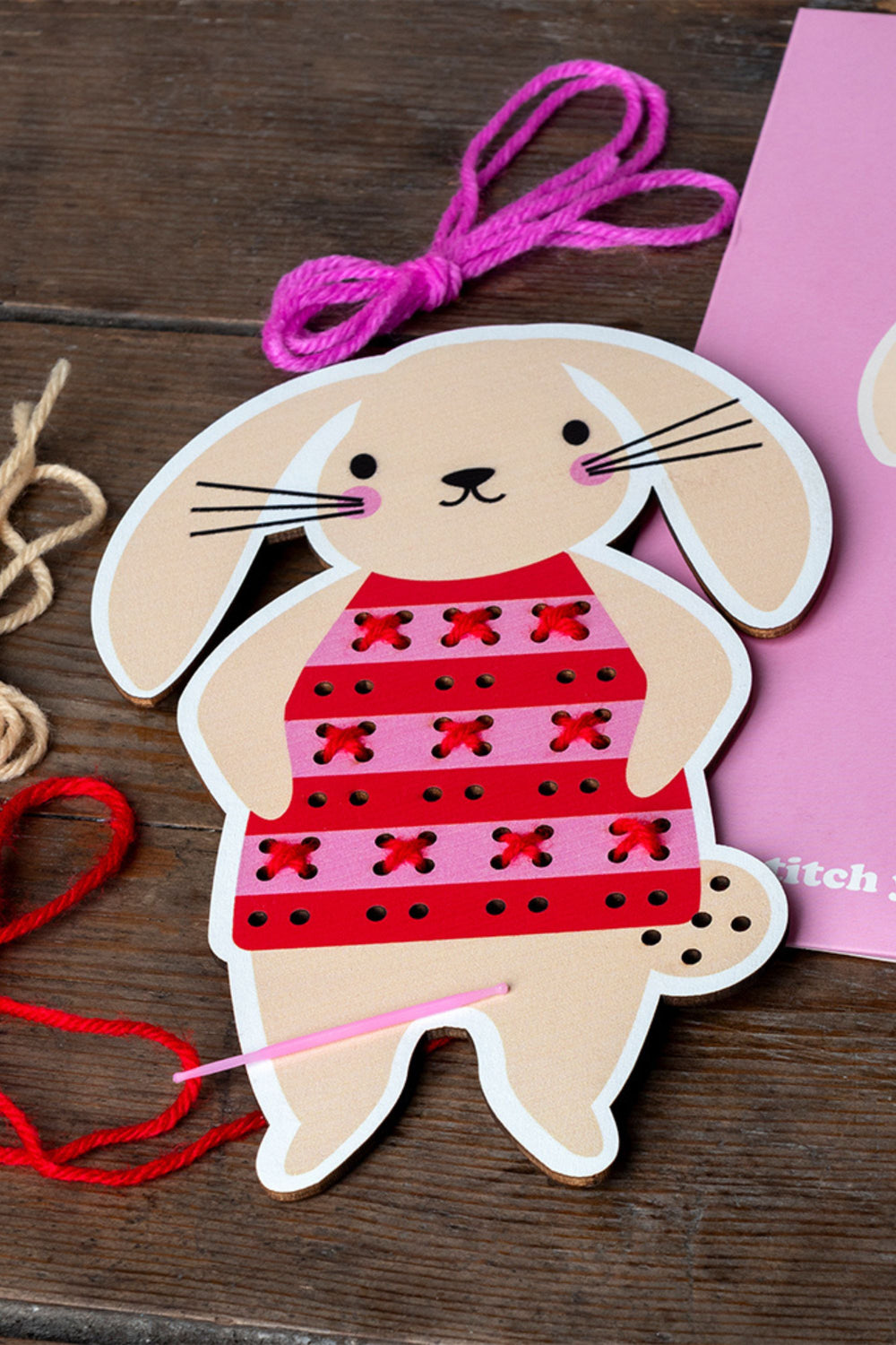 Cardboard bunny with red dress on a wooden surface