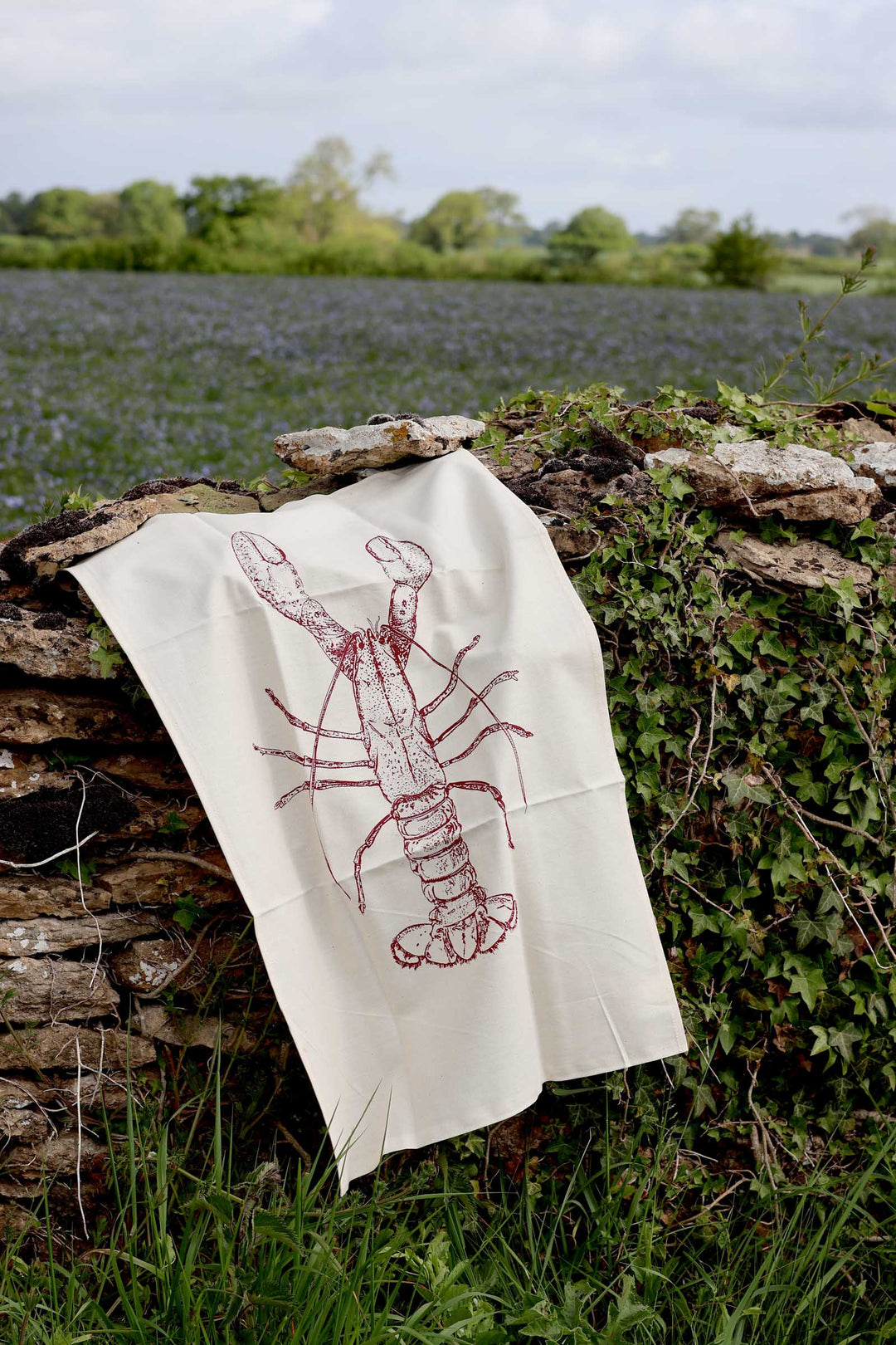 Tea towel with lobster design hanging on a stone wall outdoors