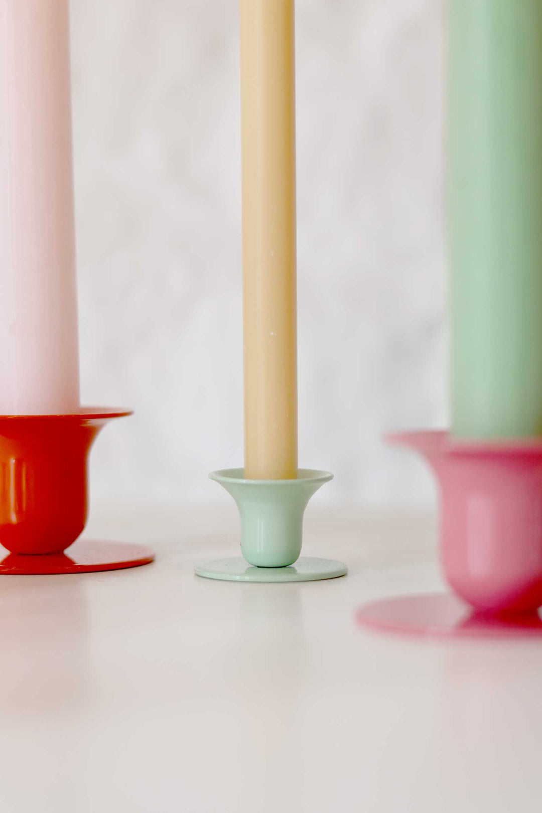 Three colorful candle holders with candles on a white background